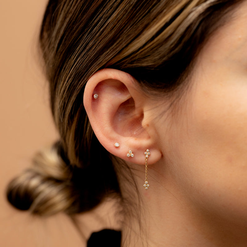 Model wears several piercings including clover diamond drop chain elegant earrings