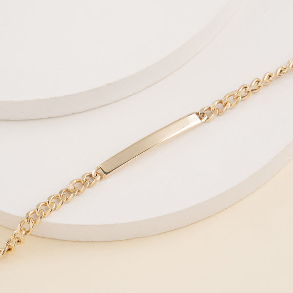 Solid gold nameplate bracelet on a chain.
