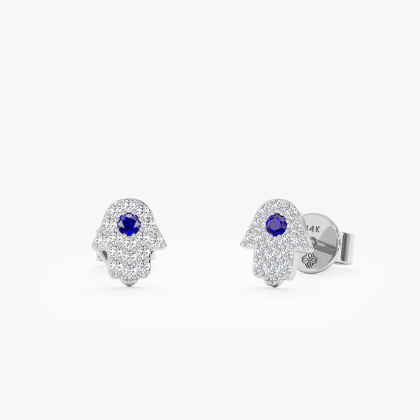 Handcrafted pair of solid 14k white gold hamsa hand stud earrings with diamonds and single blue sapphire 