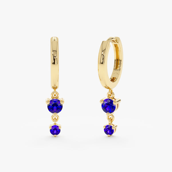 Solid gold huggies with two hanging blue sapphire stones.