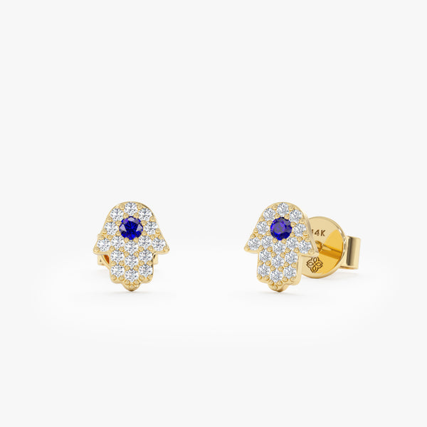 Handmade pair of solid 14k gold hamsa hand stud earrings with natural diamonds and single blue sapphire 