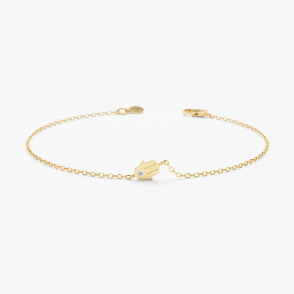 Sideways hamsa bracelet with solitaire diamond in solid gold.