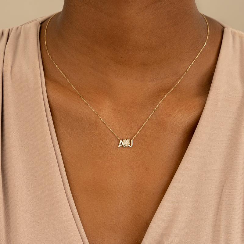 Solid gold personalized initial necklace with a heart adorned with diamonds.
