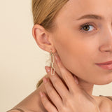 Model wears hanging chain link stud earrings lined in white diamonds