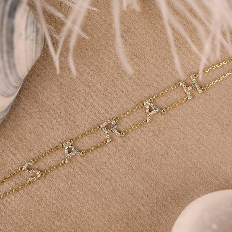 Double-chain gold bracelet with custom name spelled in diamonds.