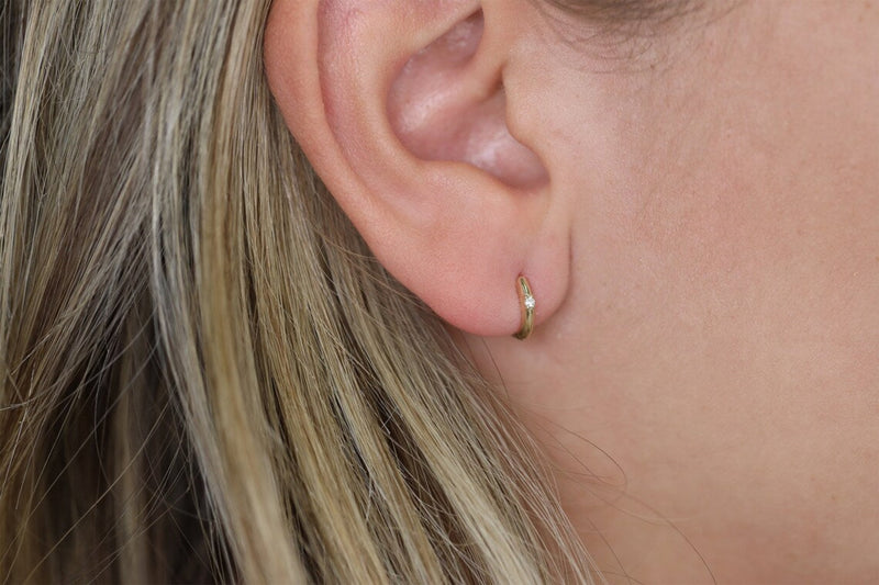 Model wears petite solid 14k gold hoop earring with single diamond
