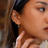 Model wears multiple piercings and asscher cut emerald charm for solid 14k gold huggies