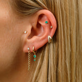 Model with multiple piercings wearing petite emerald studs in 14k gold, along with various diamond earrings.