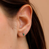 Model close up wearing dainty emerald marquise cut stone and single April birthstone diamond.