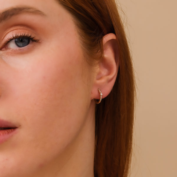 model wears minimalistic thin diamond hoop earring with single pear shaped diamond
