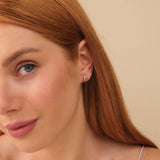 Model wears dainty double line ear huggies with April birthstone diamonds in 14k solid gold. 