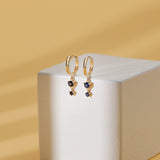 Solid gold huggie earrings with two bezel set natural blue sapphires. 