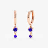 Hoop earrings with two hanging blue September birthstone Sapphires, set in solid rose gold with 3 prongs.