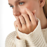 Close-up of a woman wearing a beige sweater with a focus on her hand and rings.