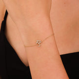 Close-up of a diamond-encrusted OM symbol on a gold bracelet.