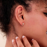 Model wearing a single gold huggie earring with a dazzling pave diamond star design