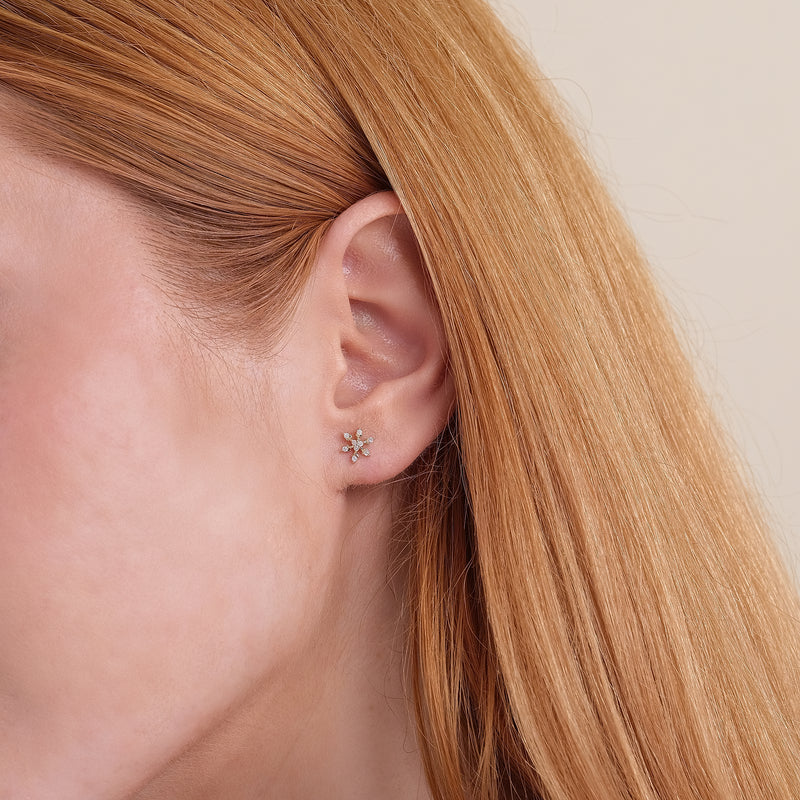 Model wearing stunning delicate diamond snowflake stud earrings in 14k solid gold.