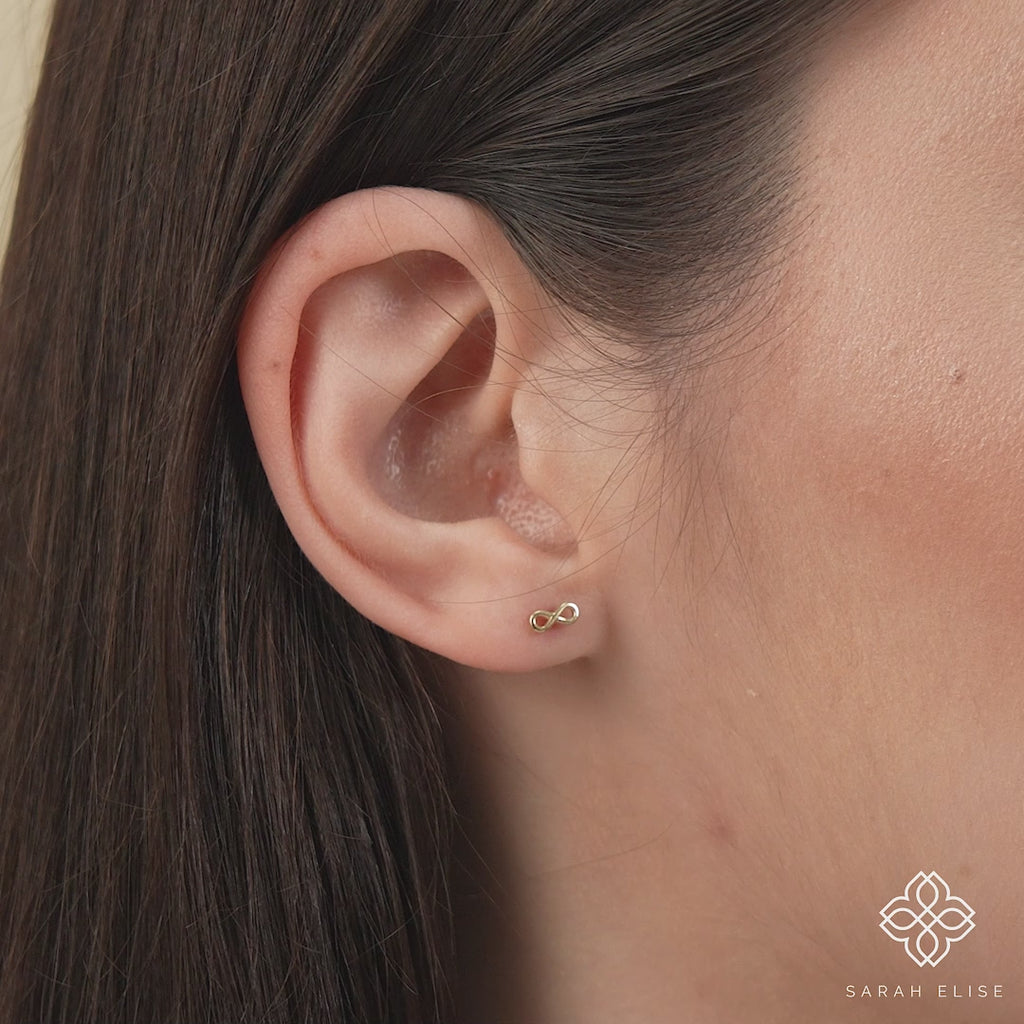 Video close up of model wearing Solid gold infinity symbol stud earring in 14k solid gold gift for her.