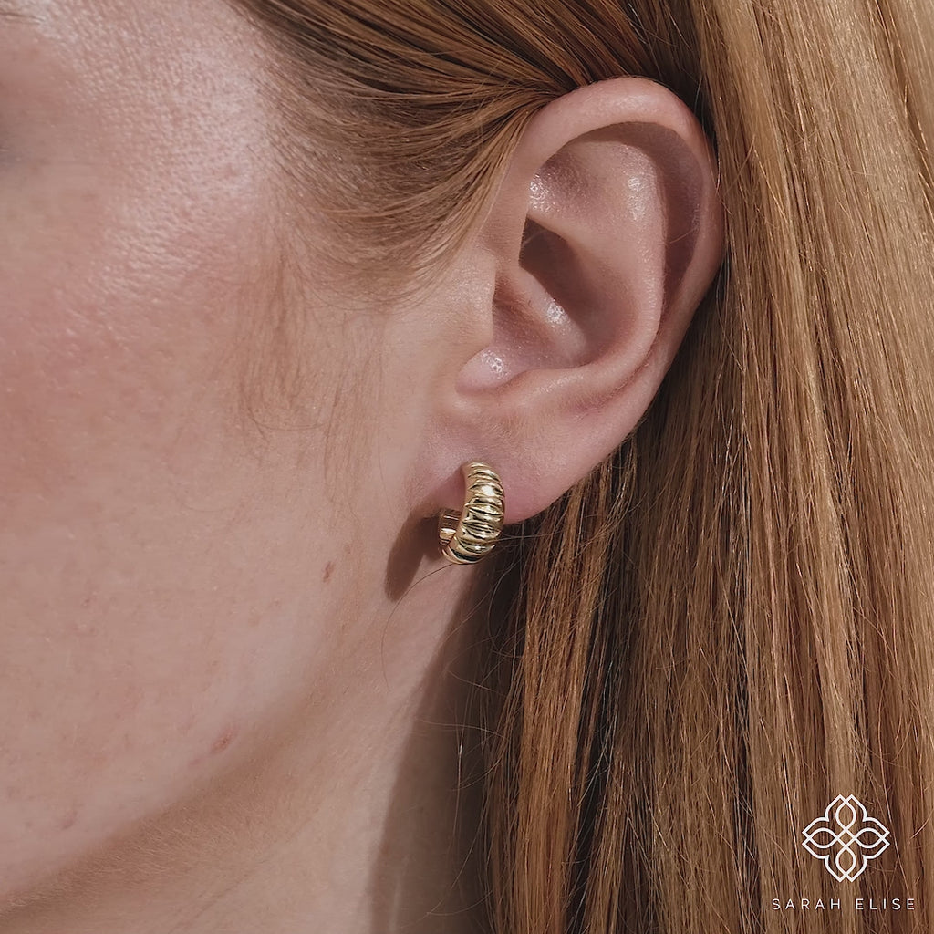 Video close up of simplistic thick ribbed earring huggie handmade in 14k solid gold. 