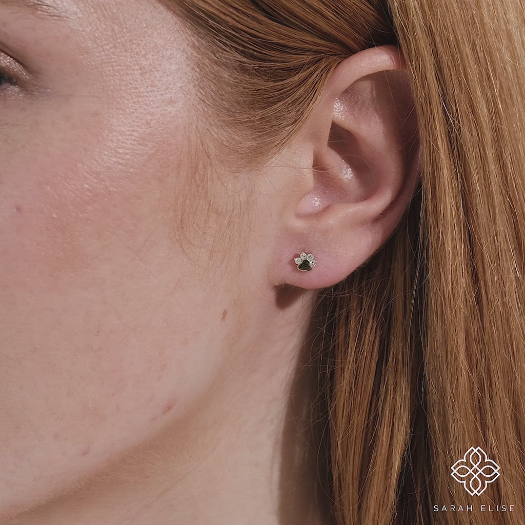 Close up model video wearing simplistic solid gold dog paw shaped earring studs with natural diamonds gift for her.