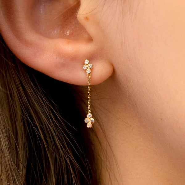 Model wears solid 14k gold drop earrings with diamond clover cluster