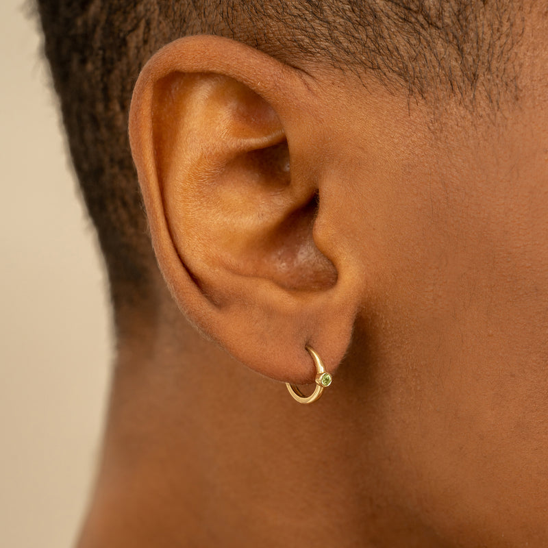 Model wears Dainty Peridot Huggie hoop earrings in solid gold