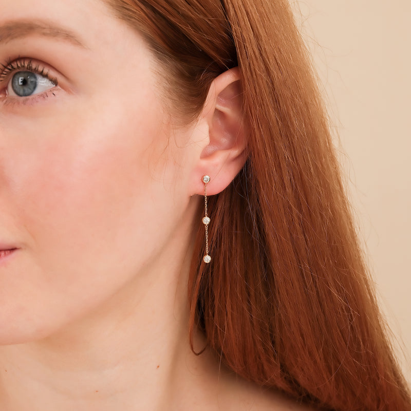 Model wears 3 bezel diamond drop earring in 14k solid gold