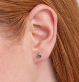 Model close up wears pear cut natural emerald stud earring made in 14k solid gold. 